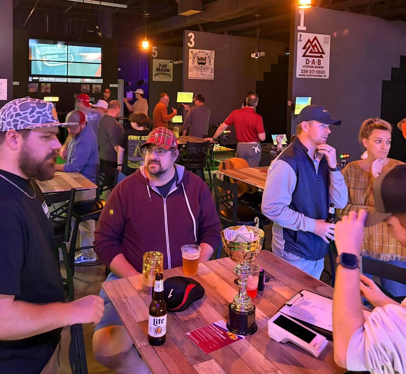 Regulars around a table of beers and the scramble trophy at Grip It Virtual Golf